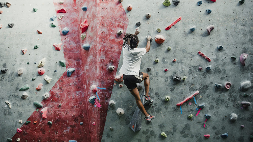 One young man is enjoying rock climbing in a climbing centre.
